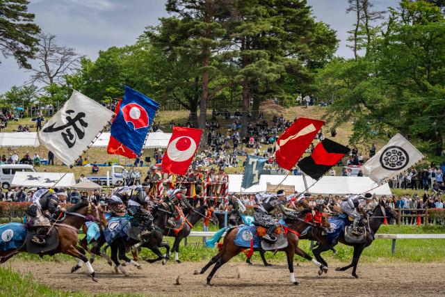 Horsemen clad in samurai armor compete in the Kachu Keiba race during the Soma Nomaoi festival at Hibarigahara field in Minamisoma, Fukushima prefecture on May 24, 2026. The Soma Nomaoi began as a way to train mounted warriors and it still looks the same a millennium later, with riders dressed in samurai armour battling it out in horseback events. (Photo by Yuichi YAMAZAKI / AFP) / To go with 'Japan-Climate-Festival-Tradition' Focus by Andrew MCKIRDY