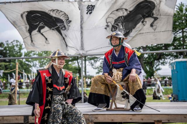 This picture taken on May 23, 2026 shows horsemen clad in samurai armor chatting during the Soma Nomaoi festival at Hibarigahara field in Minamisoma, Fukushima prefecture. The Soma Nomaoi began as a way to train mounted warriors and it still looks the same a millennium later, with riders dressed in samurai armour battling it out in horseback events. (Photo by Yuichi YAMAZAKI / AFP)