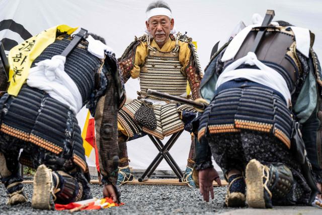 This picture taken on May 24, 2026 shows men clad in samurai armor kneeling down to Mitsukiyo Monma (C) before leaving for a parade during the Soma Nomaoi festival in Minamisoma, Fukushima prefecture. The Soma Nomaoi began as a way to train mounted warriors and it still looks the same a millennium later, with riders dressed in samurai armour battling it out in horseback events. (Photo by Yuichi YAMAZAKI / AFP)