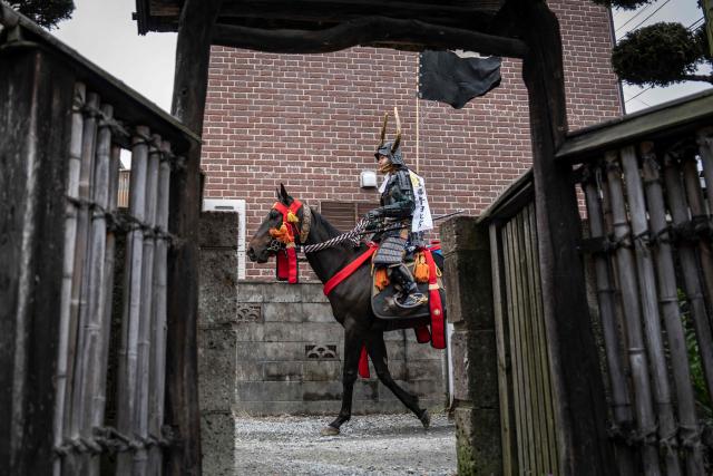 This picture taken on May 24, 2026 shows a horseman clad in samurai armor riding through a residential neighbourhood during the Soma Nomaoi festival in Minamisoma, Fukushima prefecture. The Soma Nomaoi began as a way to train mounted warriors and it still looks the same a millennium later, with riders dressed in samurai armour battling it out in horseback events. (Photo by Yuichi YAMAZAKI / AFP)