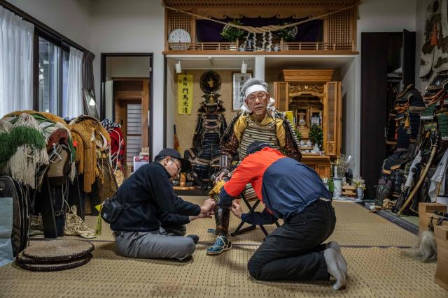 This picture taken on May 23, 2026 shows Mitsukiyo Monma (back R) wearing samurai armor with the help of family members at his house, before leaving to take part in the Soma Nomaoi festival at Minamisoma, Fukushima prefecture. The Soma Nomaoi began as a way to train mounted warriors and it still looks the same a millennium later, with riders dressed in samurai armour battling it out in horseback events. (Photo by Yuichi YAMAZAKI / AFP)