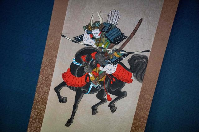 This picture taken on May 24, 2026 shows a hanging scroll featuring a horseman in samurai armour at Mitsukiyo Monma's house during the Soma Nomaoi festival in Minamisoma, Fukushima prefecture. The Soma Nomaoi began as a way to train mounted warriors and it still looks the same a millennium later, with riders dressed in samurai armour battling it out in horseback events. (Photo by Yuichi YAMAZAKI / AFP)