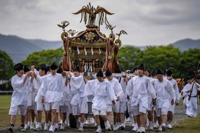 This picture taken on May 23, 2026 shows people carrying a portable shrine as they arrive at Hibarigahara field during the Soma Nomaoi festival in Minamisoma, Fukushima prefecture. The Soma Nomaoi began as a way to train mounted warriors and it still looks the same a millennium later, with riders dressed in samurai armour battling it out in horseback events. (Photo by Yuichi YAMAZAKI / AFP)