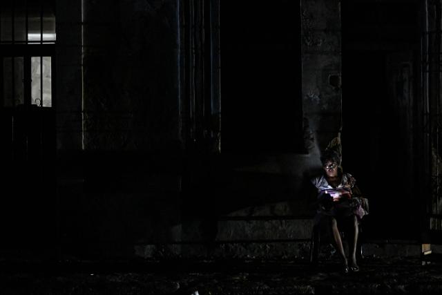 A woman checks a cell phone during a blackout outside her home in the Centro Habana neighbourhood in Havana on June 2, 2026. (Photo by ADALBERTO ROQUE / AFP)