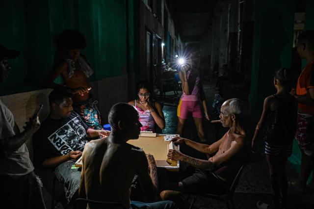People play Dominoes by the light of a cell phone flashlight during a blackout in the Centro Habana neighbourhood in Havana on June 2, 2026. (Photo by ADALBERTO ROQUE / AFP)