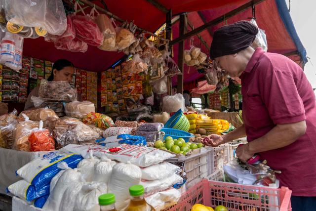A shopper (R) selects raw food ingredients at a stall in a traditional market in Jakarta on June 3, 2026. (Photo by BAY ISMOYO / AFP)