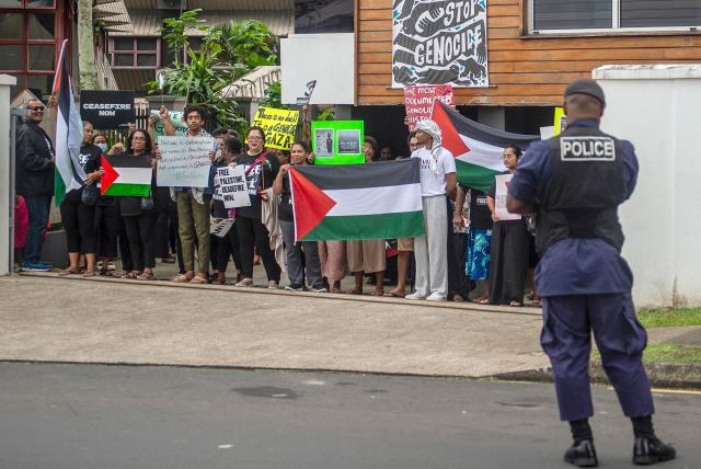 In this photo taken on June 2, 2026, a police officer stands near pro-Palestinian supporters outside the new Israeli embassy in Suva as the Israeli Foreign Minister Gideon Sa'ar and Fiji Prime Minister Sitiveni Rabuka attend a ceremony inside. (Photo by Leon Lord / AFP)
