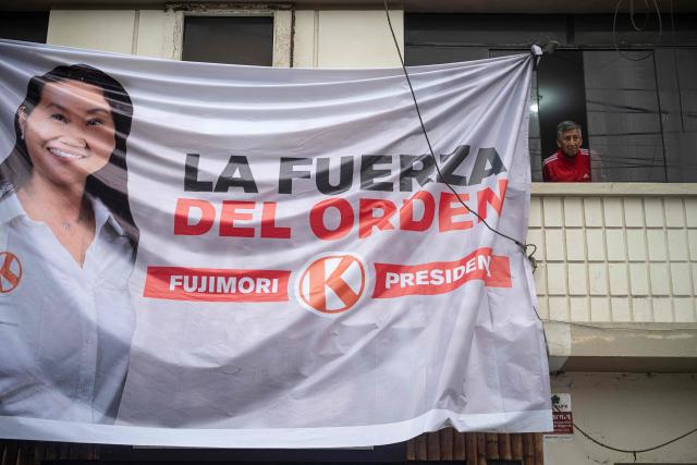 A man is seen near a banner of Peru's presidential candidate for the Fuerza Popular party, Keiko Fujimori, before a campaign rally in Huacho, north of Lima, Peru, on June 2, 2026. Peruvians will choose on June 7, 2026 their president from between the right-wing Keiko Fujimori, heir to a political dynasty that divides the nation, and the left-wing Roberto Sánchez: two diametrically opposed visions for a country plagued by instability and crime. (Photo by Ernesto BENAVIDES / AFP)