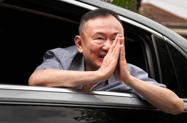 (FILES) Thailand's former prime minister Thaksin Shinawatra gestures as he arrives at his residency in a car after his release from Klong Prem Central Prison in Bangkok on May 11, 2026. Thaksin Shinawatra has met the conditions for royal pardon as part of a clemency measure marking the queen's birthday, the justice minister said on June 3, 3026. Thaksin, 76, served eight months of a one-year sentence for corruption and abuse of power before he was released on parole last month due to his age. (Photo by Chanakarn LAOSARAKHAM / AFP)