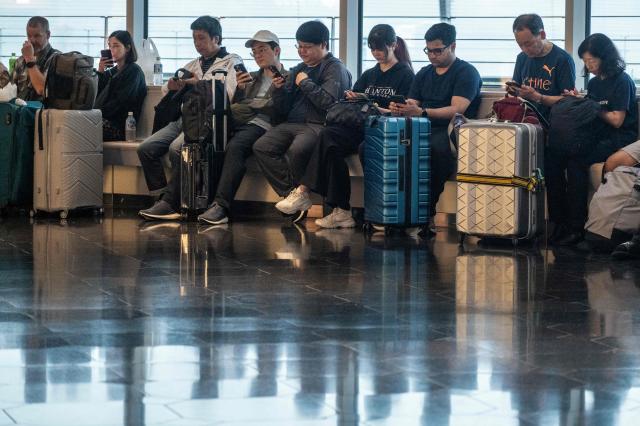 Passengers wait at the International Terminal at Haneda airport after flights were cancelled or severely delayed because of severe tropical storm Jangmi in Tokyo on June 3, 2026. A severe tropical storm moved towards Tokyo on June 3, with forecasters warning of floods after torrential rain battered swathes of the country and prompted calls to evacuate for hundreds of thousands of people. (Photo by Andrew CABALLERO-REYNOLDS / AFP)