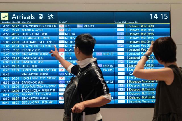 Passengers look at the arrival flight board at the International Terminal at Haneda airport after flights were cancelled or severely delayed because of severe tropical storm Jangmi in Tokyo on June 3, 2026. A severe tropical storm moved towards Tokyo on June 3, with forecasters warning of floods after torrential rain battered swathes of the country and prompted calls to evacuate for hundreds of thousands of people. (Photo by Andrew CABALLERO-REYNOLDS / AFP)
