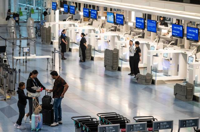 Passengers wait near empty check in counters at the International Terminal at Haneda airport after flights were cancelled or severely delayed because of severe tropical storm Jangmi in Tokyo on June 3, 2026. A severe tropical storm moved towards Tokyo on June 3, with forecasters warning of floods after torrential rain battered swathes of the country and prompted calls to evacuate for hundreds of thousands of people. (Photo by Andrew CABALLERO-REYNOLDS / AFP)