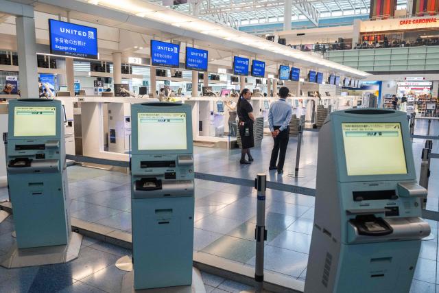Airline staff wait at empty checkin counters at the International Terminal at Haneda airport after flights were cancelled or severely delayed because of severe tropical storm Jangmi in Tokyo on June 3, 2026. A severe tropical storm moved towards Tokyo on June 3, with forecasters warning of floods after torrential rain battered swathes of the country and prompted calls to evacuate for hundreds of thousands of people. (Photo by Andrew CABALLERO-REYNOLDS / AFP)