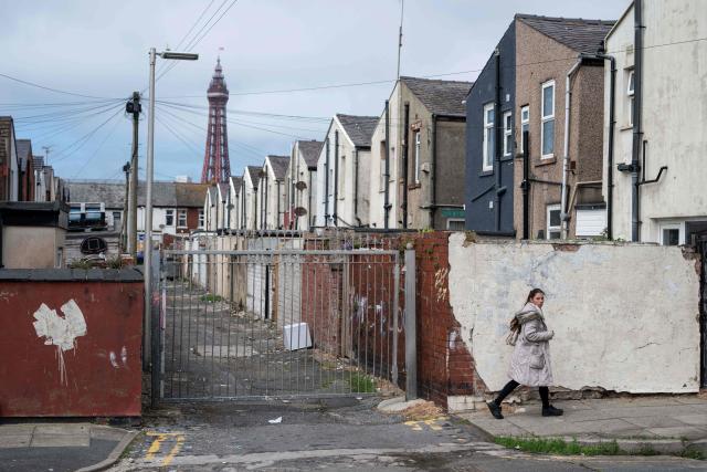A woman walks past a gated rear alleyway leading to residential properties in central Blackpool, north-west England on June 2, 2026. (Photo by Oli SCARFF / AFP)