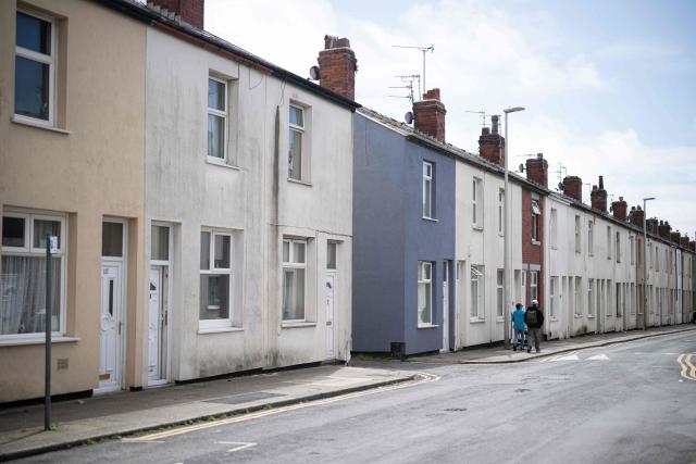 People walk past residential properties along a street in central Blackpool, north-west England on June 2, 2026. (Photo by Oli SCARFF / AFP)