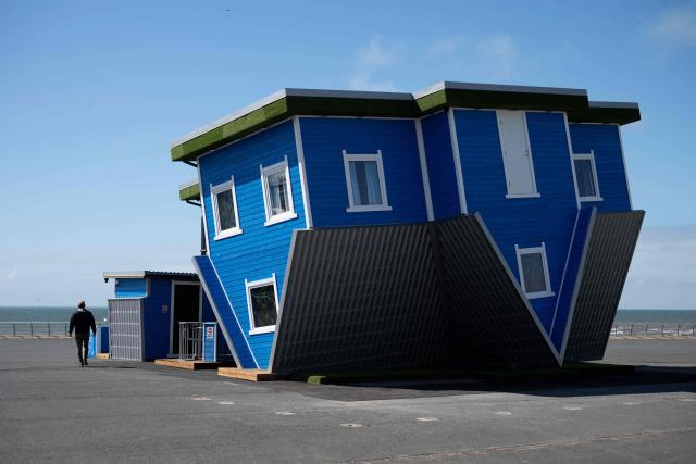 A man walks past the 'Upside Down House', an attraction located on the Promenade in central Blackpool, north-west England on June 2, 2026. (Photo by Oli SCARFF / AFP)