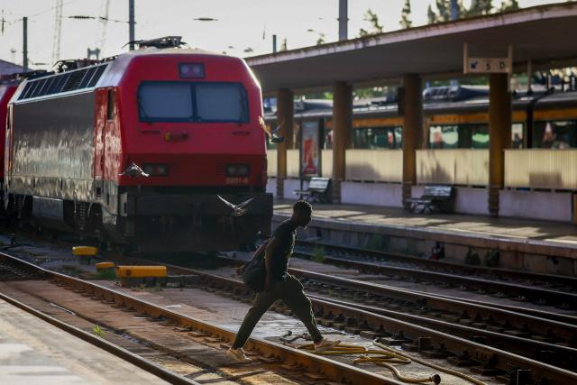 A man crosses the tracks as trains stand idle at Santa Apolonia train station during a nationwide general strike in Lisbon on June 3, 2026. Public transport and municipal services were severely disrupted in Portugal on Wednesday due to a 24-hour general strike over proposed labour reforms. The stoppage hit transport companies as well as waste collection, hospitals and schools, according to the General Confederation of Portuguese Workers (CGTP). (Photo by PATRICIA DE MELO MOREIRA / AFP)