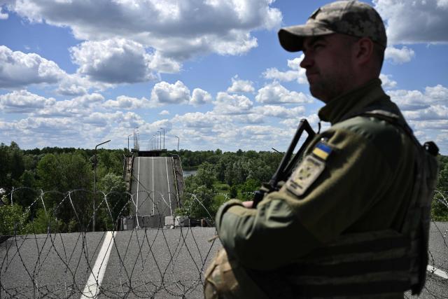 Officer of the State Border Guard Service of Ukraine, the deputy commander of a border outpost with the call sign “Brat,” stands on a destroyed bridge over the Dnipro River, which forms the state border between Ukraine and Belarus in the Chernigiv region, on June 1, 2026, amid the Russian invasion of Ukraine. (Photo by Genya SAVILOV / AFP)