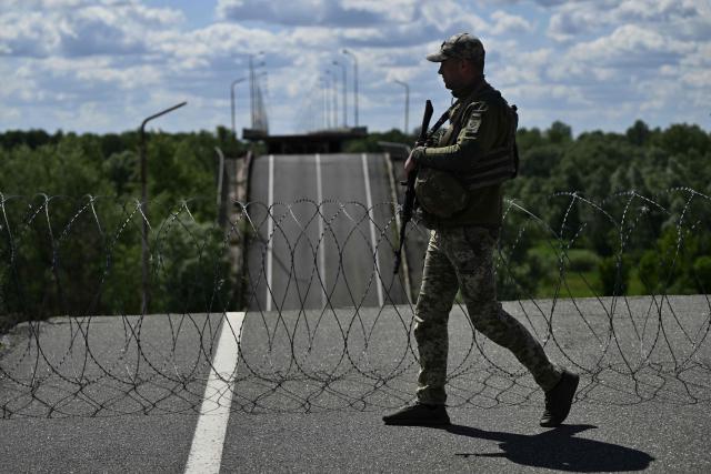 Officer of the State Border Guard Service of Ukraine, the deputy commander of a border outpost with the call sign “Brat,” walks on a destroyed bridge over the Dnipro River, which forms the state border between Ukraine and Belarus in the Chernigiv region, on June 1, 2026, amid the Russian invasion of Ukraine. (Photo by Genya SAVILOV / AFP)