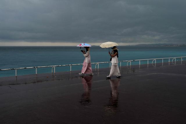 Two women carry umbrellas as they walk in the rain on the "Promenade des anglais" in the French riviera city of Nice on June 2, 2026. (Photo by Valery HACHE / AFP)
