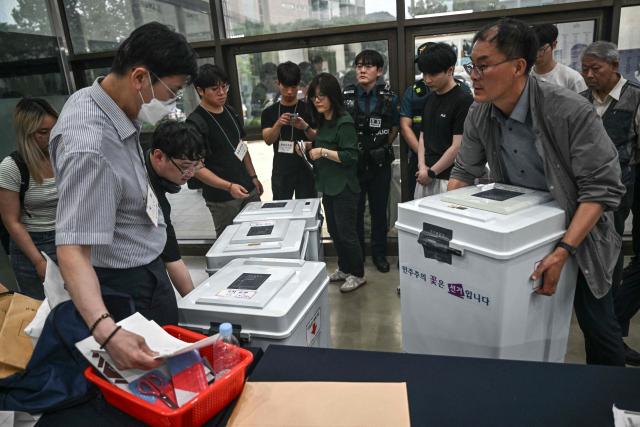 Election officials carry ballot boxes at a counting station for the local elections in Seoul on June 3, 2026. (Photo by Pedro Pardo / AFP)