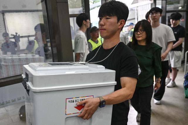An election official carries a ballot box at a counting station for the local elections in Seoul on June 3, 2026. (Photo by Pedro Pardo / AFP)