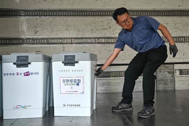 An election official unloads ballot boxes from a truck at a counting station for the local elections in Seoul on June 3, 2026. (Photo by Pedro Pardo / AFP)