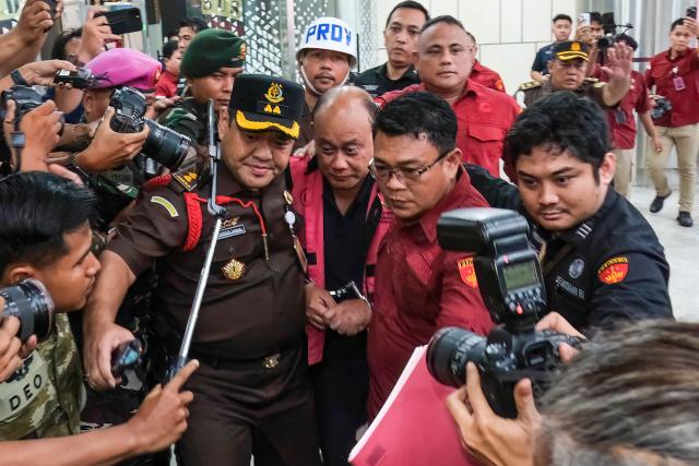 Dadan Hindayana (C), former head of Indonesia's free school meals programme, is escorted by officers from the Attorney General's Office and Indonesian military personnel as he leaves the Attorney General's Office building in Jakarta on June 3, 2026, following questioning over alleged misappropriation in the implementation of the programme. Indonesian authorities on June 3 arrested the head of the body responsible for President Prabowo Subianto's signature free school meals programme, a day after he was removed on concerns including food quality. (Photo by BAY ISMOYO / AFP)