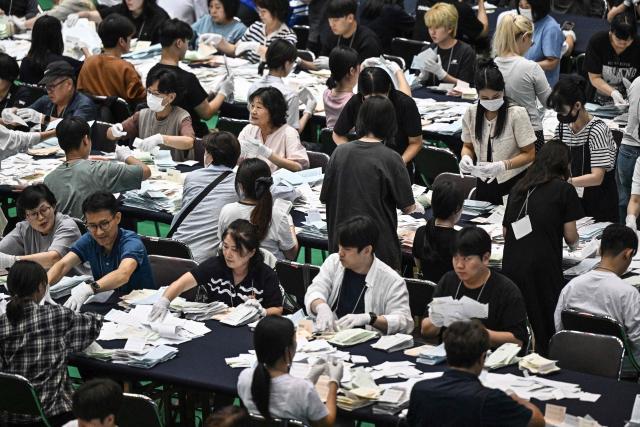 Election officials sort through ballots at a counting station for the local elections in Seoul on June 3, 2026. (Photo by Pedro Pardo / AFP)
