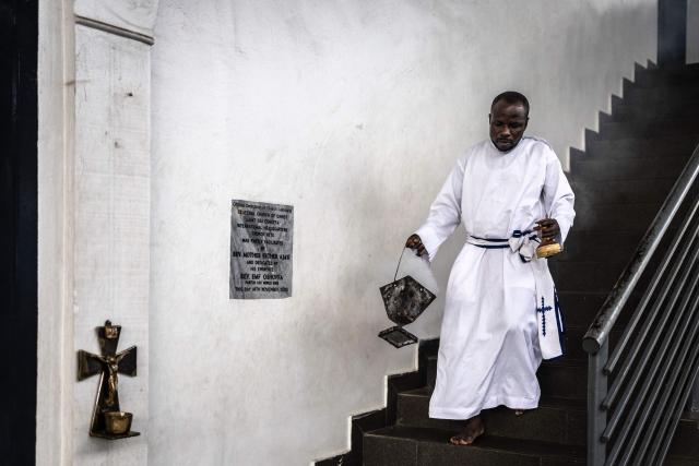 A worshipper carrying burning incense walks down the stairs during a service at the Celestial Church of Christ International Headquarters in the Ketu neighbourhood of Lagos, on June 3, 2026. (Photo by OLYMPIA DE MAISMONT / AFP)