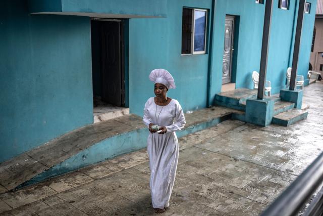 A worshipper holding money walks across the church compound during a service at the Celestial Church of Christ International Headquarters in the Ketu neighbourhood of Lagos, on June 3, 2026. (Photo by OLYMPIA DE MAISMONT / AFP)