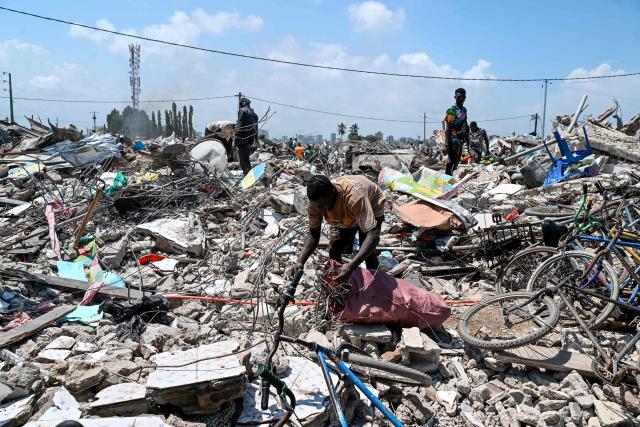 A resident scavenges through rubble after the destruction of the precarious Zimbabwe neighbourhood during an eviction operation in the Port-Bouet neighbourhood in Abidjan on June 3, 2026. (Photo by Sia KAMBOU / AFP)