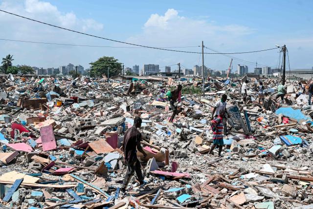 Young men walk over rubble in search of various objects after the destruction of the precarious Zimbabwe neighbourhood during an eviction operation in the Port-Bouet neighbourhood in Abidjan on June 3, 2026. (Photo by Sia KAMBOU / AFP)