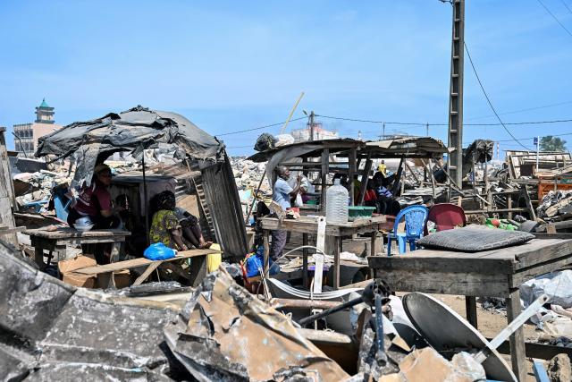 Residents sit under shelters after the destruction of the precarious Zimbabwe neighbourhood during an eviction operation in the Port-Bouet neighbourhood in Abidjan on June 3, 2026. (Photo by Sia KAMBOU / AFP)