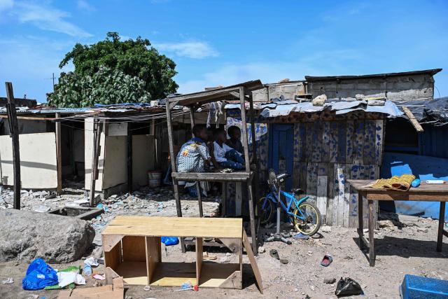 Three children sit on a table in front of their home before the destruction of the precarious Zimbabwe neighbourhood during an eviction operation in the Port-Bouet neighbourhood in Abidjan on June 3, 2026. (Photo by Sia KAMBOU / AFP)