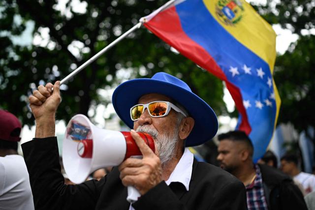 A man waves a Venezuelan national flag as workers and pensioners take part in a march demanding better working conditions and a political transition, outside the US embassy in Caracas on June 3, 2026. (Photo by Federico PARRA / AFP)