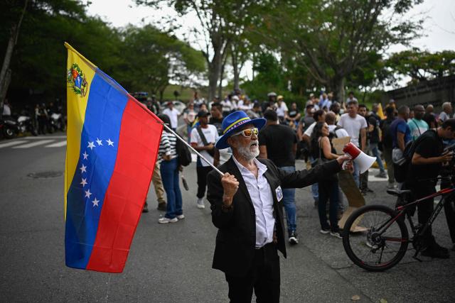 A man waves a Venezuelan national flag as workers and pensioners take part in a march demanding better working conditions and a political transition, outside the US embassy in Caracas on June 3, 2026. (Photo by Federico PARRA / AFP)