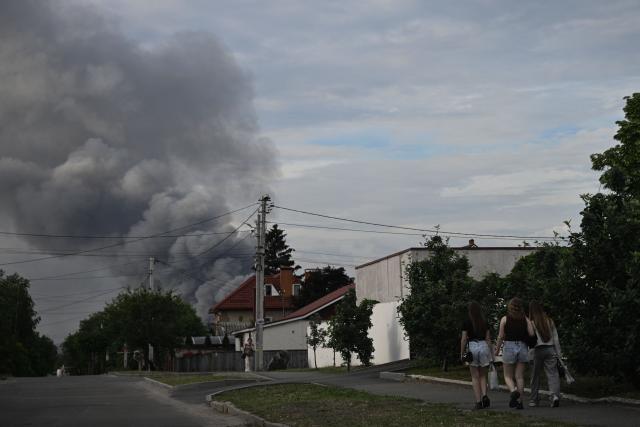 Pedestrians walk along a street as smoke rises in the background, following Russian strikes in the city of Dnipro on June 3, 2026, amid the Russian invasion of Ukraine. (Photo by Genya SAVILOV / AFP)