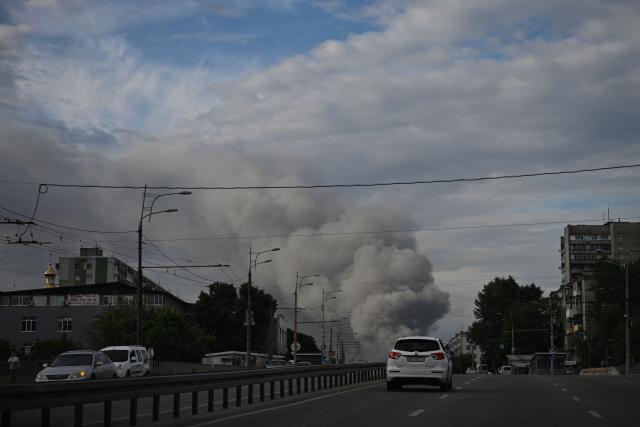 Cars drive along down street as smoke rises in the background, following Russian strikes in the city of Dnipro on June 3, 2026, amid the Russian invasion of Ukraine. (Photo by Genya SAVILOV / AFP)