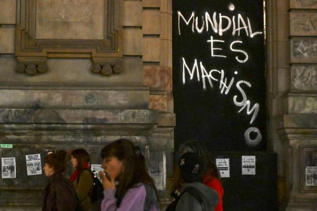 Women walk past a graffiti reading ‘The World Cup is sexist’ during a ‘Not One Less’ march in Buenos Aires on June 3, 2026. Thousands of people, mostly women, took to the streets across Argentina on June 3, to denounce femicides and demand public policies against gender-based violence, in marches called by the feminist movement ‘Not One Less’ amid shock over the recent killing of a teenage girl. (Photo by Luis ROBAYO / AFP)