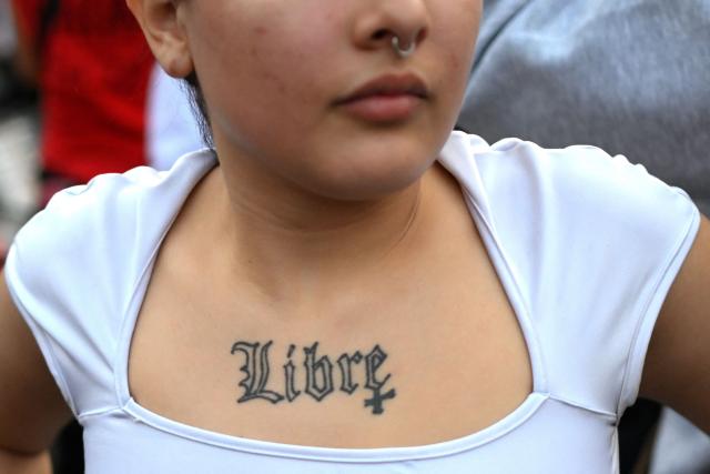 A woman shows a tattoo reading ‘free’ during a ‘Not One Less’ march in Buenos Aires on June 3, 2026. Thousands of people, mostly women, took to the streets across Argentina on June 3, to denounce femicides and demand public policies against gender-based violence, in marches called by the feminist movement ‘Not One Less’ amid shock over the recent killing of a teenage girl. (Photo by Luis ROBAYO / AFP)