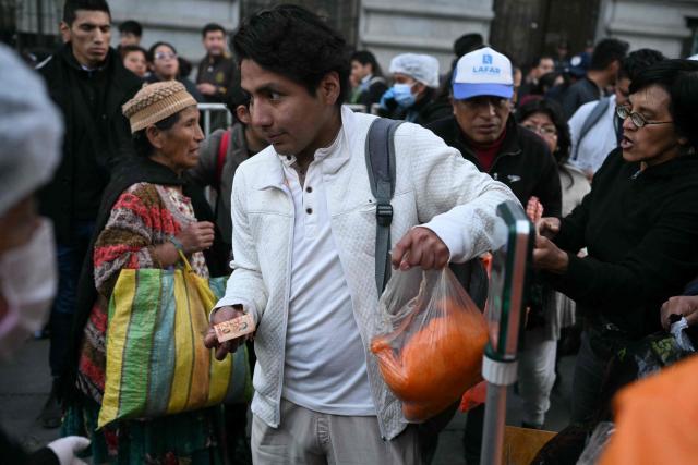 A man buys a chicken from people selling poultry out of a truck amid food shortages caused by the blockades, in La Paz on June 3, 2026. Hundreds of demonstrators demanded on June 1, in Bolivia’s political capital the resignation of President Rodrigo Paz, as one month of protests and road blockades continues across the country with no solution to the crisis in sight. (Photo by Marvin RECINOS / AFP)