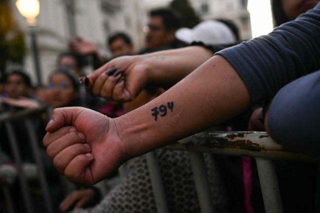 People show their turn numbers written on their arms as they stand in line to buy chicken amid food shortages caused by the blockades, in La Paz on June 3, 2026. Hundreds of demonstrators demanded on June 1, in Bolivia’s political capital the resignation of President Rodrigo Paz, as one month of protests and road blockades continues across the country with no solution to the crisis in sight. (Photo by Marvin RECINOS / AFP)