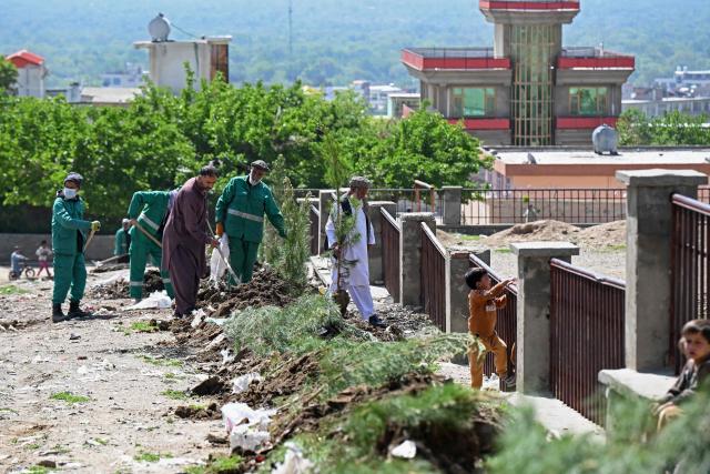This photograph taken on April 20, 2026 shows Afghan municipality workers and residents planting trees next to a park in Charikar district, Parwan province. Under the shade of recently planted poplars in northeastern Afghanistan, village leader Ghulam Ali Poya is proud to see residents rediscover the value of trees after years of wartime deforestation from the 1979 Soviet invasion until the fall of the first Taliban government in the early 2000s. Efforts are now underway to revive the landscape in communities across Afghanistan. (Photo by Wakil KOHSAR / AFP)