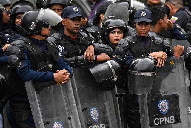 Venezuela's Bolivarian National Police officers stand guard during a prisoners transfer outside El Helicoide prison in Caracas on June 3, 2026. (Photo by Juan BARRETO / AFP)