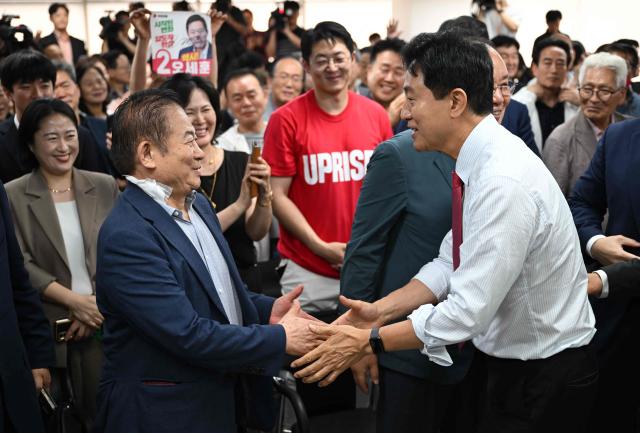 Mayoral candidate Oh Se-hoon (R) of South Korea's main opposition People Power Party celebrates his victory with party members after national TV predicted his win in the local elections at his campaign camp in Seoul on June 4, 2026. (Photo by Jung Yeon-je / AFP)