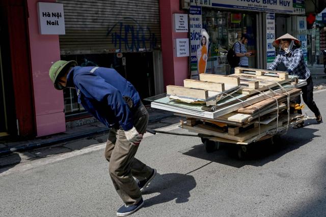 People move waste on a cart along a street in Hanoi on June 4, 2026. (Photo by Nhac NGUYEN / AFP)