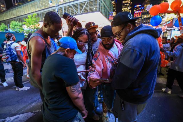 Knicks fans watch Game 1 of the NBA Finals between the New York Knicks and the San Antonio Spurs highlights on their phones in New York City on June 3, 2026. (Photo by TIMOTHY A.CLARY / AFP)