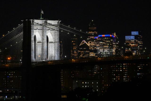 Manhattan buildings lit up in orange and blue near the Brooklyn Bridge are seen during Game 1 of the NBA Finals between the New York Knicks and the San Antonio Spurs in New York, on June 3, 2026. (Photo by ANGELA WEISS / AFP)