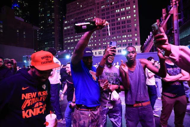 Knicks fans celebrate while watching Game 1 of the NBA Finals between the New York Knicks and the San Antonio Spurs highlights on their phones in New York City on June 3, 2026. (Photo by TIMOTHY A.CLARY / AFP)